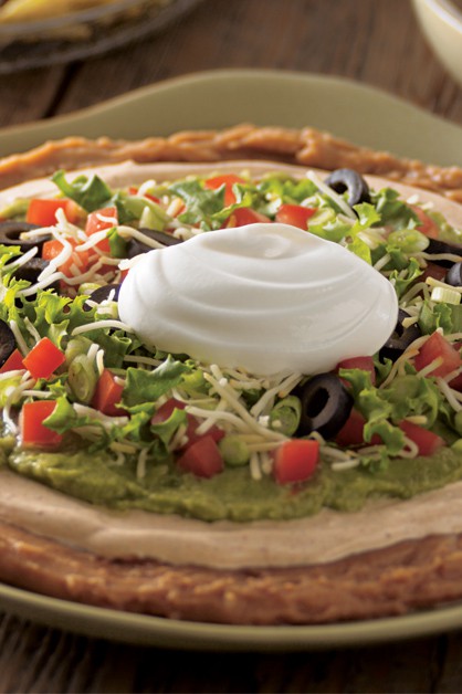 Mexican Layered bean dip on plate with sour cream on top