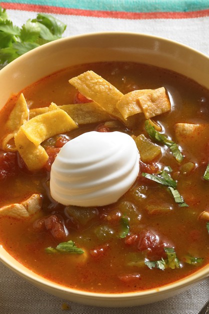 sopa de tortilla de pollo en un bol con crema agria encima