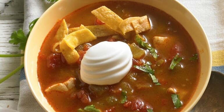 sopa de tortilla de pollo en un bol con crema agria encima