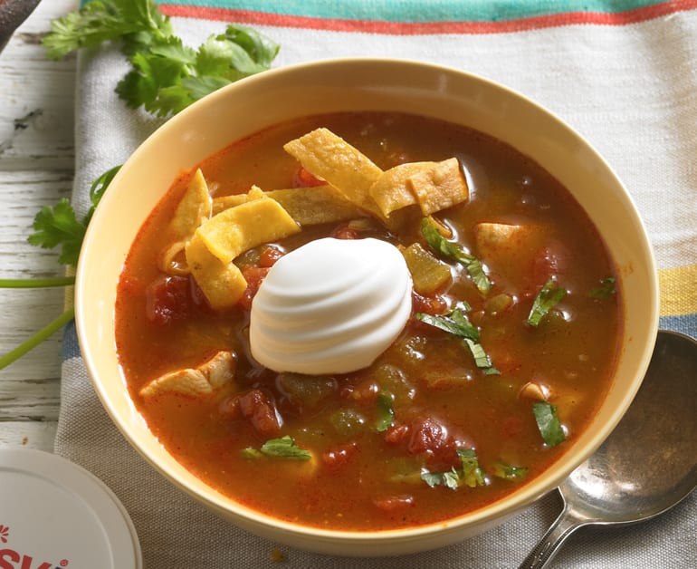 sopa de tortilla de pollo en un bol con crema agria encima