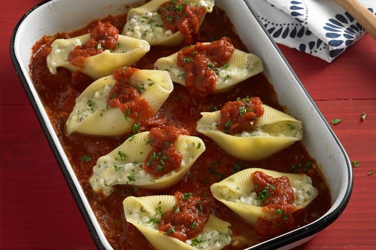 Three cheese stuffed shells in pan with red sauce