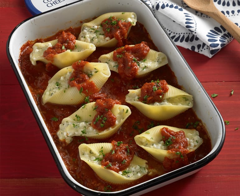 Three cheese stuffed shells in pan with red sauce