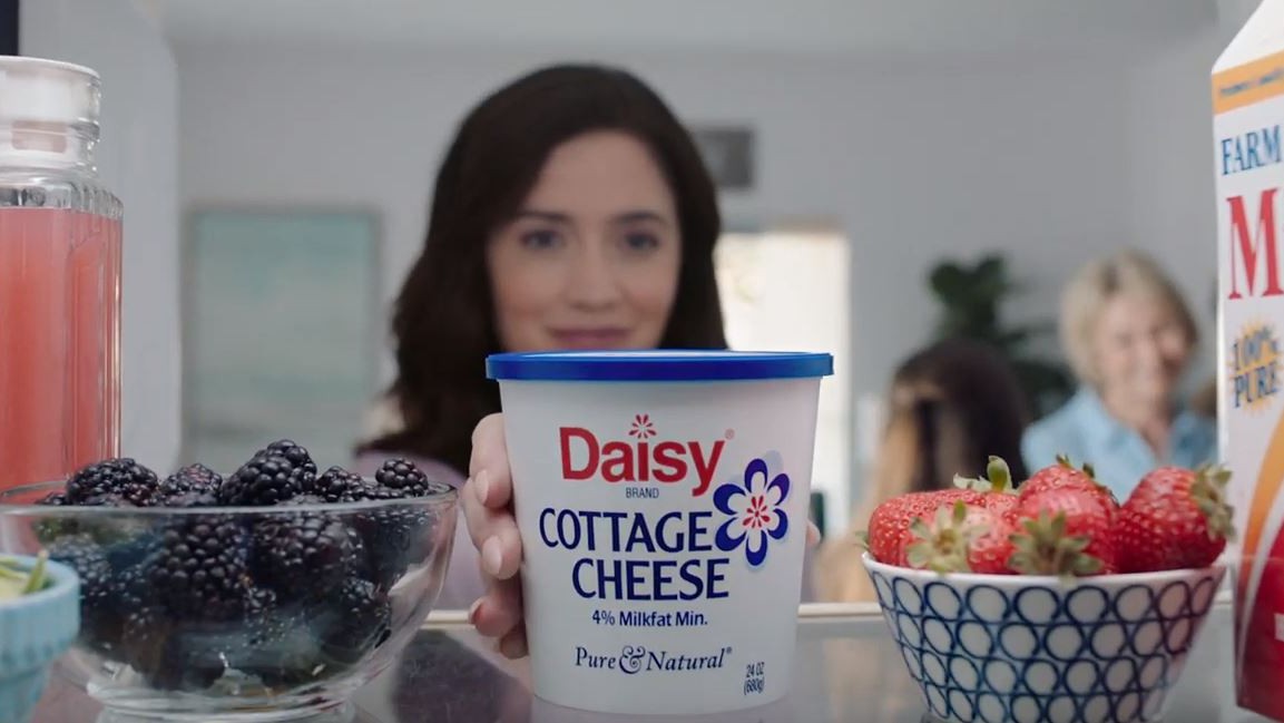 Woman grabbing daisy cottage cheese from fridge
